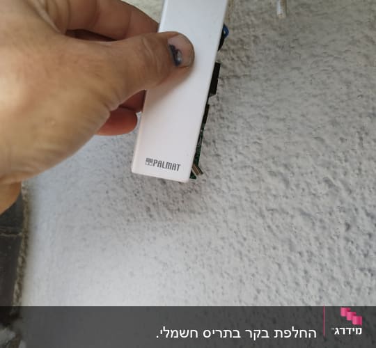 יד מחזיקה בקרת תריסים חשמליים על קיר
